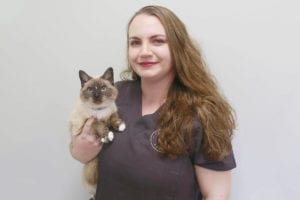 A woman in a dark uniform holds a fluffy cat