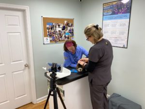 Two women are attentively working on a dog in a well-lit room