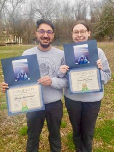 Two individuals proudly hold certificates featuring a photo of a dog