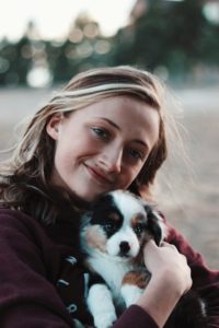A young person holds a small, fluffy puppy