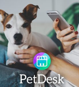 A person uses a smartphone beside a small dog, featuring PetDesk