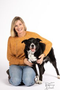 A smiling black and white dog sits closely with a person